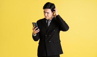 portrait de asiatique Masculin homme d'affaire. portant une costume et posant sur une Jaune Contexte photo