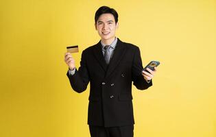 portrait de asiatique Masculin homme d'affaire. portant une costume et posant sur une Jaune Contexte photo