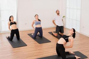 une yoga prof et sa groupe de élèves faire de base yoga pose dans une salle de cours dans une aptitude centre dans le studio. photo