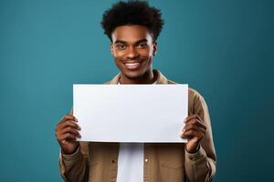 une gars de africain apparence détient dans le sien mains une blanc Vide feuille de papier avec une endroit pour l'écriture ou maquette. photo