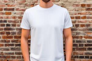 Jeune homme portant Vide blanc T-shirt dans de face de le brique mur. maquette T-shirt modèle. photo