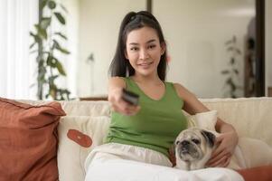 content Jeune asiatique femme câlins et dépenses temps avec mignonne chien dans vivant chambre. photo