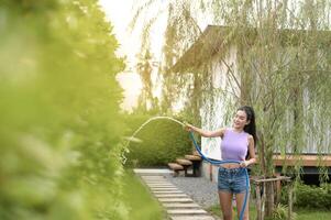 Jeune asiatique femme arrosage les plantes dans le jardin en plein air à maison. photo