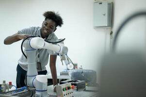 stagiaire la robotique ingénieur apprentissage avec programmation et manipuler robot main, industriel la robotique conception, haute technologie facilité, moderne machine apprentissage. Masse production automatiques. photo