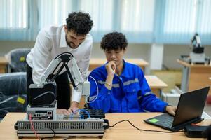 stagiaire la robotique ingénieur apprentissage avec programmation et manipuler robot main, industriel la robotique conception, haute technologie facilité, moderne machine apprentissage. Masse production automatiques. photo