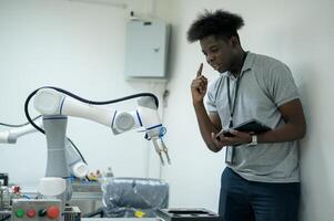 stagiaire la robotique ingénieur apprentissage avec programmation et manipuler robot main, industriel la robotique conception, haute technologie facilité, moderne machine apprentissage. Masse production automatiques. photo