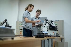 stagiaire la robotique ingénieur apprentissage avec programmation et manipuler robot main, industriel la robotique conception, haute technologie facilité, moderne machine apprentissage. Masse production automatiques. photo