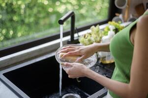 asiatique femme la lessive vaisselle dans le cuisine évier à Accueil photo