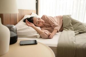 Jeune asiatique femme en train de dormir dans le lit dans chambre à Accueil photo