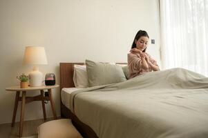 Jeune asiatique femme élongation dans lit après veille en haut dans le Matin photo