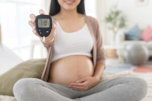 Enceinte femme vérification du sang sucre niveau par en utilisant numérique glucose mètre, santé se soucier, médecine, diabète, glycémie concept photo