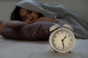 asiatique femme dans lit en retard en essayant à sommeil Souffrance insomnie, sans sommeil ou effrayé dans une cauchemar, à la recherche triste inquiet et stressé. fatigué et mal de crâne ou migraine veille en haut dans le milieu de le nuit. photo