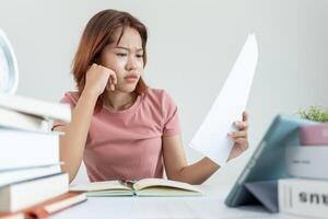 une étudiante asiatique a de l'anxiété à cause des examens, les femmes se préparent aux tests et apprennent les leçons à la bibliothèque. stress, désespoir, hâte, incompréhension lecture, découragement, attente, connaissance photo