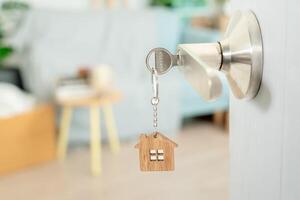 déménagement, déménagement. la clé a été insérée dans la porte de la nouvelle maison, à l'intérieur de la pièce se trouvait une boîte en carton contenant des effets personnels et des meubles. emménager dans l'appartement ou la copropriété photo