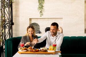 Jeune couple ayant le déjeuner et en buvant Frais pressé jus dans le restaurant photo