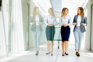 deux Jeune affaires femmes en marchant et discuter dans le Bureau couloir photo