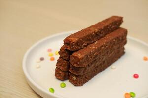 Chocolat bars sur une blanc assiette avec coloré des sucreries dans le Contexte photo