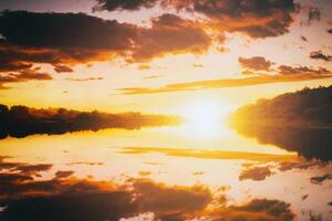 lever du soleil ou le coucher du soleil sur une Lac ou rivière avec nuageux ciel réflexion dans le l'eau dans heure d'été. esthétique de ancien film. photo