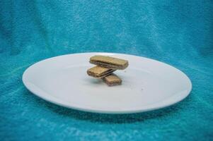 nombreuses gaufrettes ou gaufrettes arrangé sur une plaine blanc assiette sur une turquoise Contexte photo