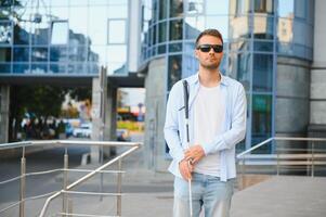 Jeune Beau aveugle homme en marchant avec bâton dans ville photo