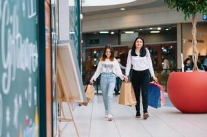 magnifique Jeune maman et adolescent fille sont en portant achats Sacs et souriant tandis que Faire achats dans centre commercial. famille achats photo