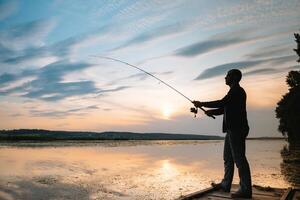 pêche. filage à le coucher du soleil. silhouette de une pêcheur. photo
