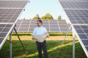 Sénior Masculin ingénieur inspecte solaire panneaux sur cultiver. nettoyer énergie. photo