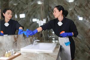 Jeune femmes de chambre nettoyage dans salle de bains photo