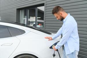 élégant homme inserts prise de courant dans le électrique voiture mise en charge prise photo