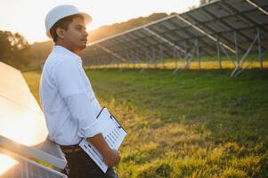 portrait Jeune Indien technicien ou directeur portant formel chiffons permanent avec solaire panneau. renouvelable énergie, homme permanent franchi bras, copie espace photo