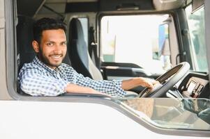 Jeune Indien un camion chauffeur séance derrière pilotage roue dans une cabine photo