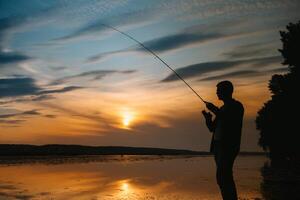 pêcheur à le coucher du soleil sur le rivière .beau été paysage avec le coucher du soleil sur le rivière. pêche. filage à le coucher du soleil. silhouette de une pêcheur. photo