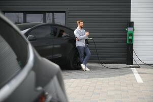 une homme des stands près une mise en charge station et des charges le sien électrique voiture photo