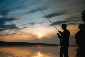 pêche. filage à le coucher du soleil. silhouette de une pêcheur. photo