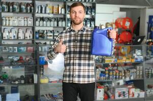 vendeur homme avec boîte de moteur pétrole dans auto boutique photo