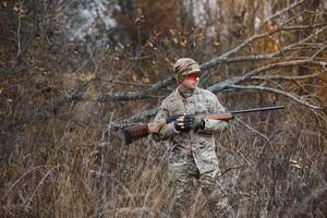 chasseur Beau gars avec arme. chasseur dépenser loisir chasse. chasse équipement. brutal masculin passe-temps. homme observer la nature Contexte. chasseur tenir fusil. sécurité mesures. Naturel environnement photo