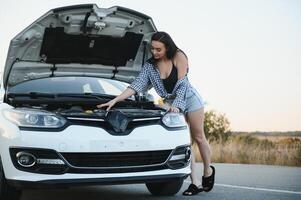 magnifique sexy femme près une cassé auto. confus femme Est-ce que ne pas connaître quoi à faire photo