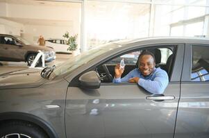 Heureux acheteur de véhicule africain à l'intérieur de sa nouvelle voiture avec clé de voiture photo