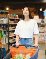 content Jeune femme à la recherche à produit à épicerie magasin. souriant femme achats dans supermarché photo