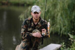 pêche dans rivière.a pêcheur avec une pêche barre sur le rivière banque. homme pêcheur captures une poisson pêche au brochet, filage bobine, poisson, breg rivières. - le concept de une rural partir. article à propos pêche photo