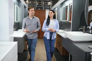 Jeune couple choisir Nouveau salle de bains meubles à le plomberie magasin avec beaucoup de sanitaire des biens photo