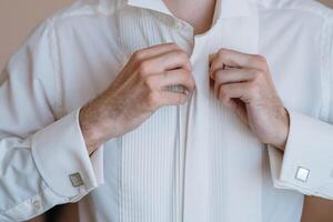 Masculin mains sur une Contexte de une blanc chemise, manche chemise avec boutons de manchette et montres, photographié fermer photo