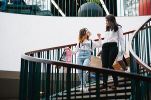 magnifique Jeune maman et adolescent fille sont en portant achats Sacs et souriant tandis que Faire achats dans centre commercial. famille achats photo