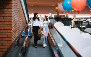 magnifique Jeune maman et adolescent fille sont en portant achats Sacs et souriant tandis que Faire achats dans centre commercial. famille achats photo