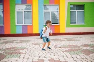 retour à école. content souriant garçon dans des lunettes est Aller à école pour le premier temps. enfant avec sac à dos et livre en plein air. début de cours. premier journée de tomber photo