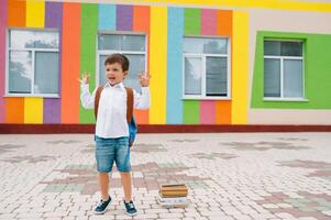 retour à école. content souriant garçon dans des lunettes est Aller à école pour le premier temps. enfant avec sac à dos et livre en plein air. début de cours. premier journée de tomber photo