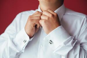 Masculin mains sur une Contexte de une blanc chemise, manche chemise avec boutons de manchette et montres, photographié fermer. photo