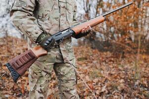 chasseur Beau gars avec arme. chasseur dépenser loisir chasse. chasse équipement. brutal masculin passe-temps. homme observer la nature Contexte. chasseur tenir fusil. sécurité mesures. Naturel environnement photo