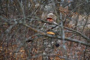 chasse, guerre, armée et gens concept - Jeune soldat, ranger ou chasseur avec pistolet en marchant dans forêt photo