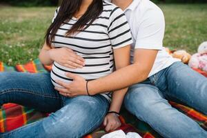 image de Enceinte couple. mari émouvant le sien épouse ventre avec mains. Enceinte femme en plein air. photo